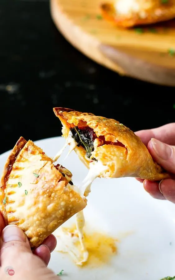 pulling a caprese empanada apart with melty cheese