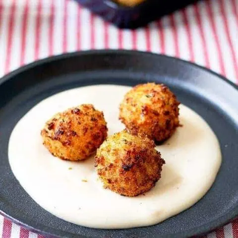 3 Arancini on top cheesy alfredo sauce
