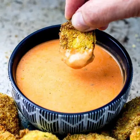 air fryer pickle being dipped into a bowl of sauce
