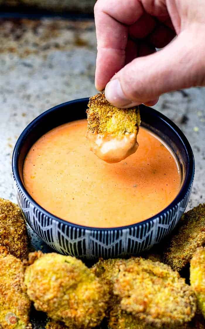 air fryer pickle being dipped into a bowl of sauce