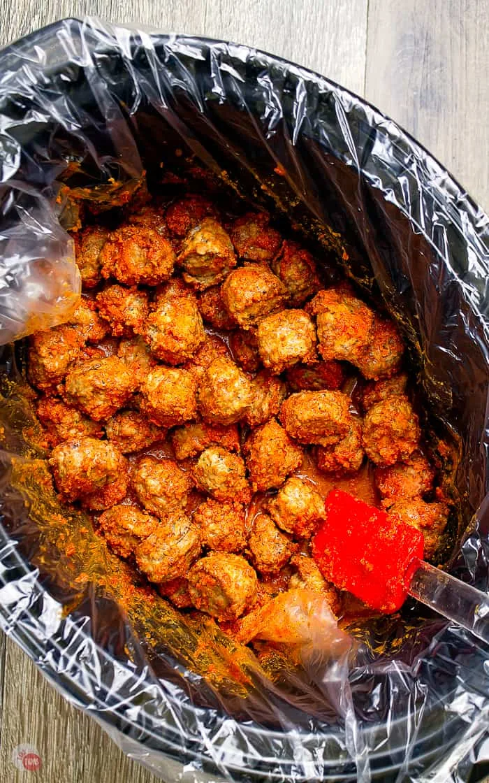 cocktail meatballs in slow cooker with red spatula