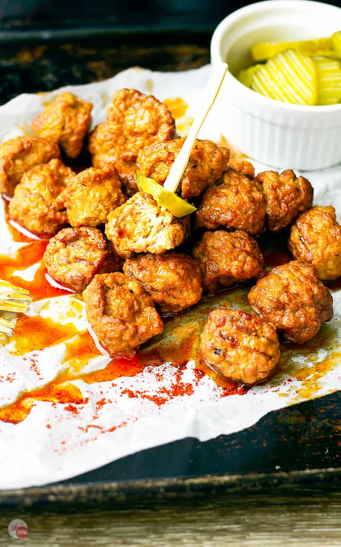 close up of hot chicken meatballs and pickles on toothpicks