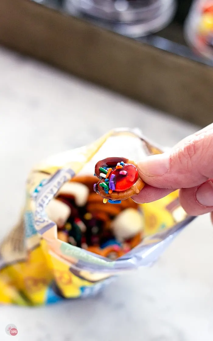 mini pretzel with chocolate sauce and sprinkles held in between fingers