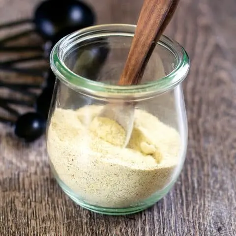 adobo seasoning in a small jar with stirring spoon