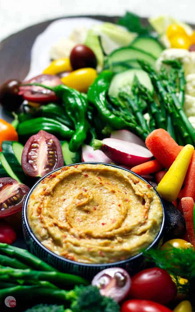 close up of hummus in a bowl on crudite platter