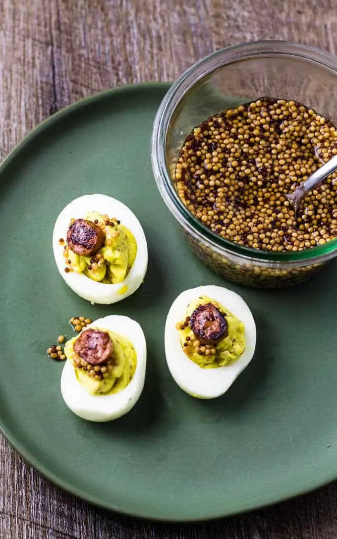 overhead view of eggs on a plate with a bowl of mustard seeds next to it