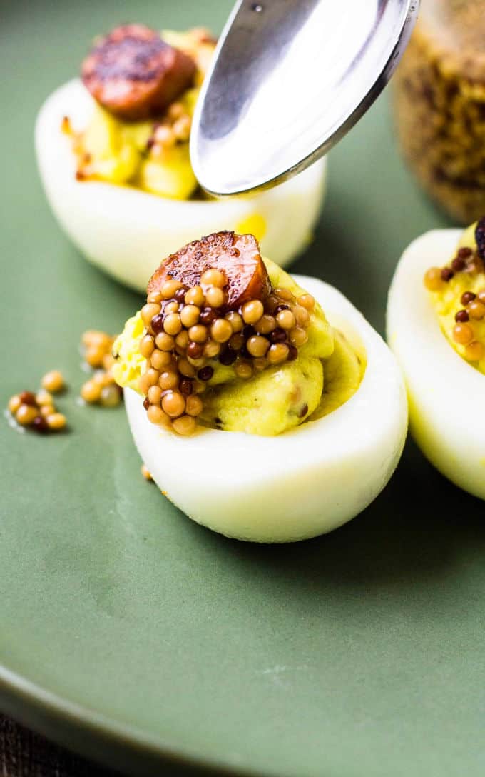 spoon over deviled eggs with mustard seeds