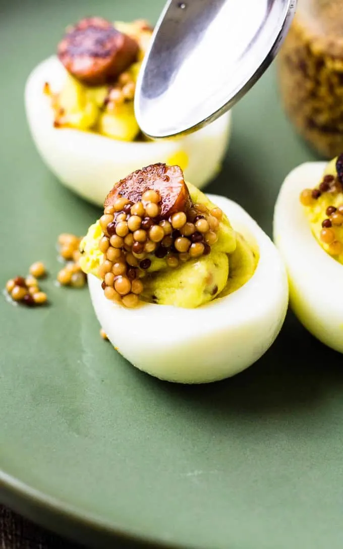 spoon over deviled eggs with mustard seeds