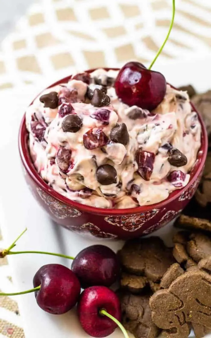 close up of Drunken Cherry Garcia Dip with a full Cherry in it and Cherries out side of it with animal crackers on a white platter.