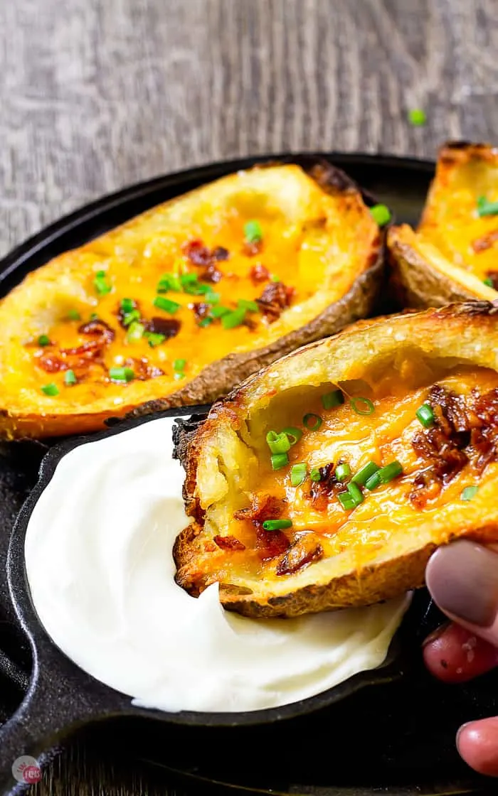 hand dipping potato skin in sour cream