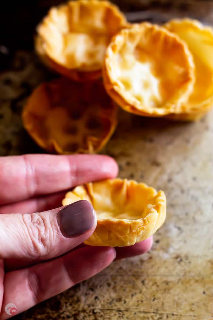 hand holding a round pastry cups