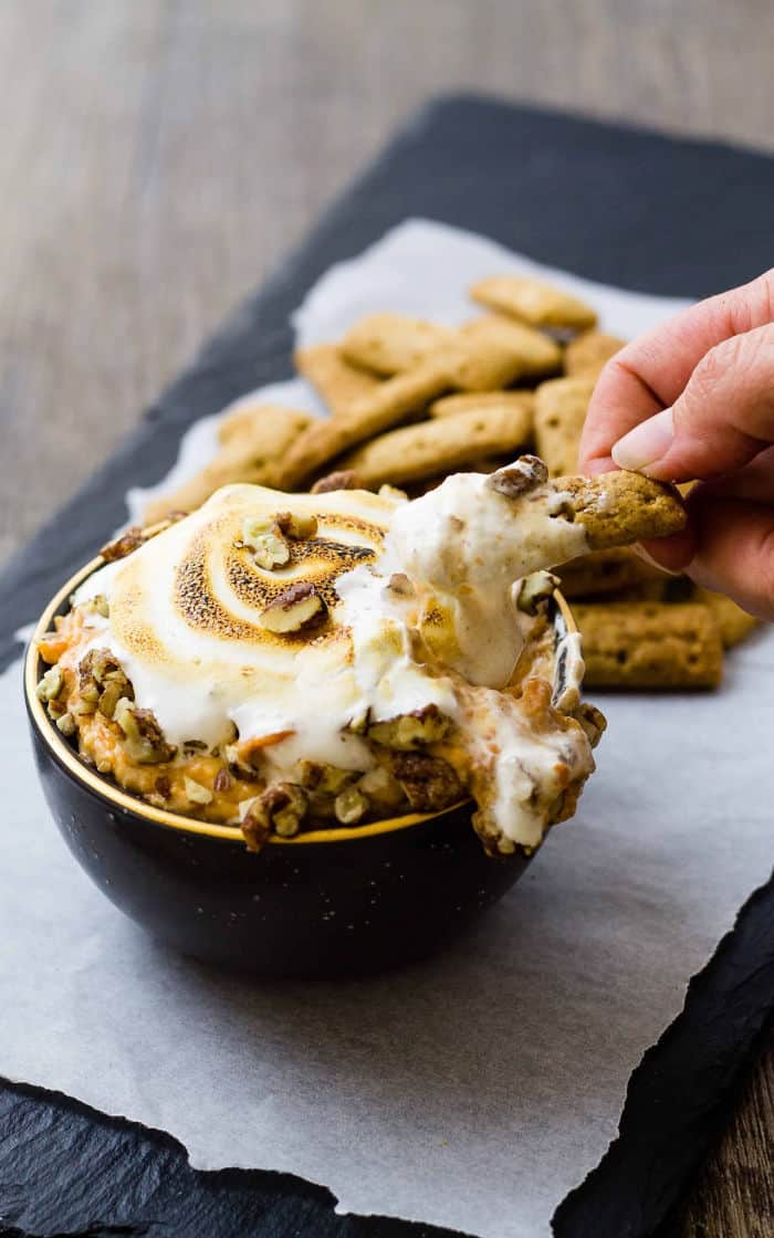 hand dipping a cinnamon stick into dip