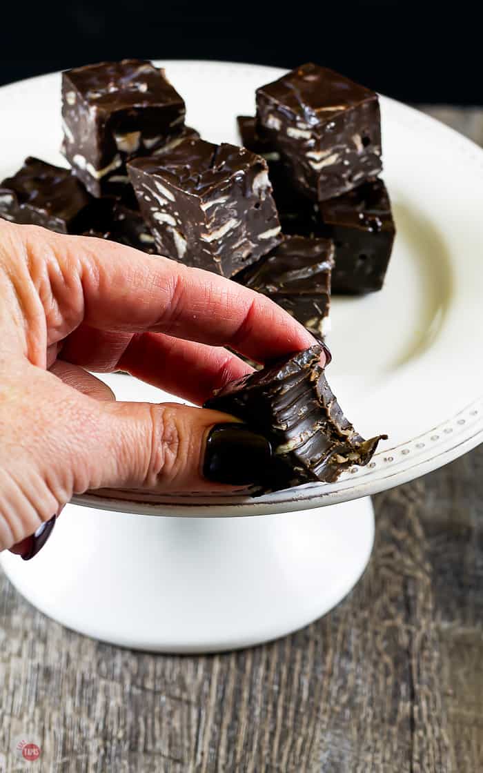 hand holding a piece of chocolate fudge with a bite taken out of it