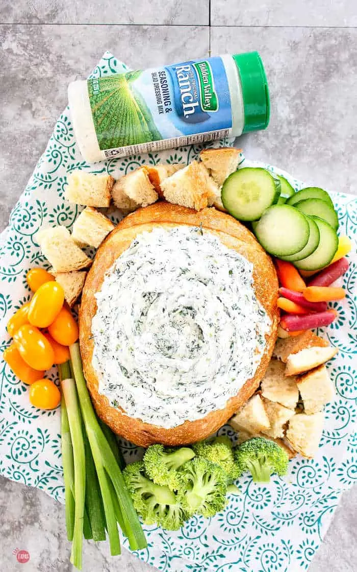 overhead picture of bread bowl with dip and sliced cucumbers