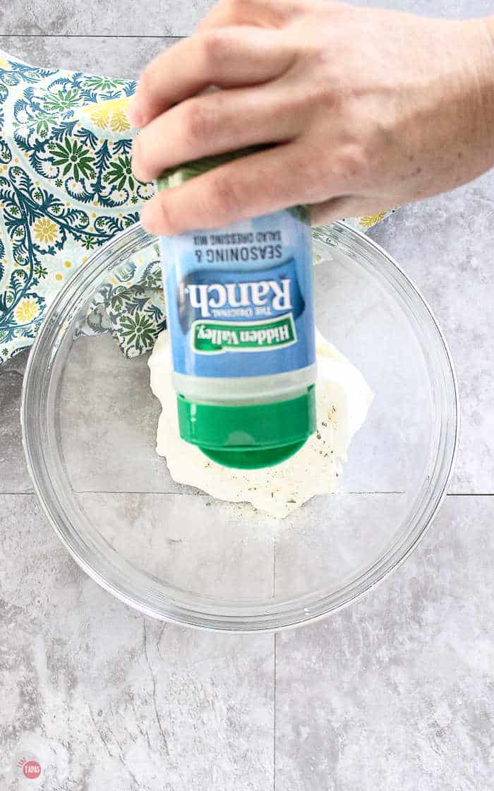 Ranch seasoning being poured into sour cream