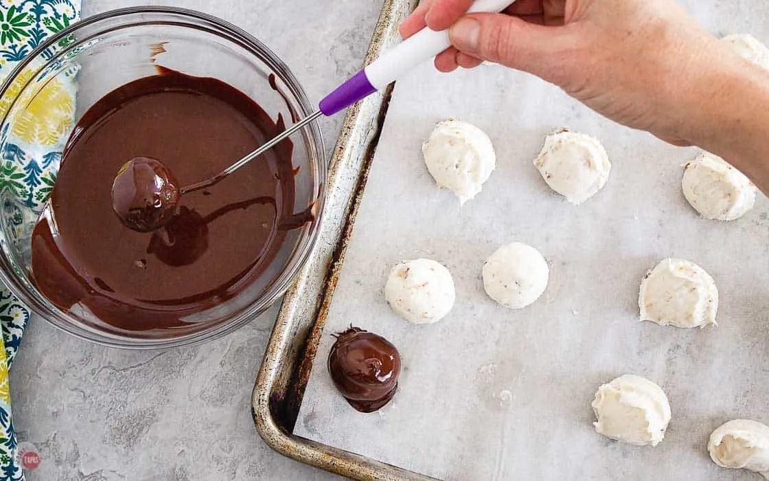 bourbon balls being dipped in melted chocolate