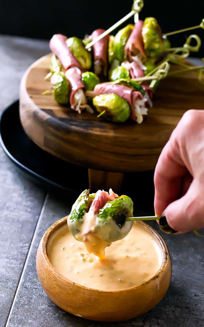 hand dipping a skewer in a bowl of dip