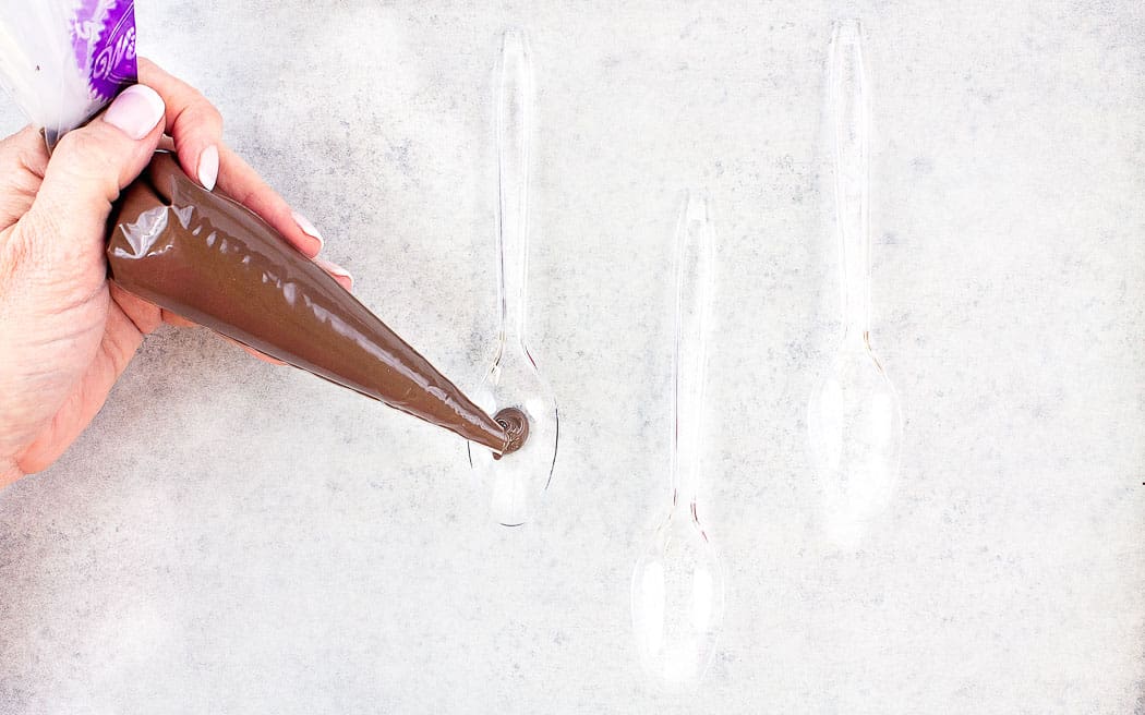 piping melted chocolate into a plastic spoon