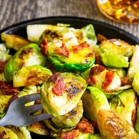 fork with a sprout on it above a plate of sprouts
