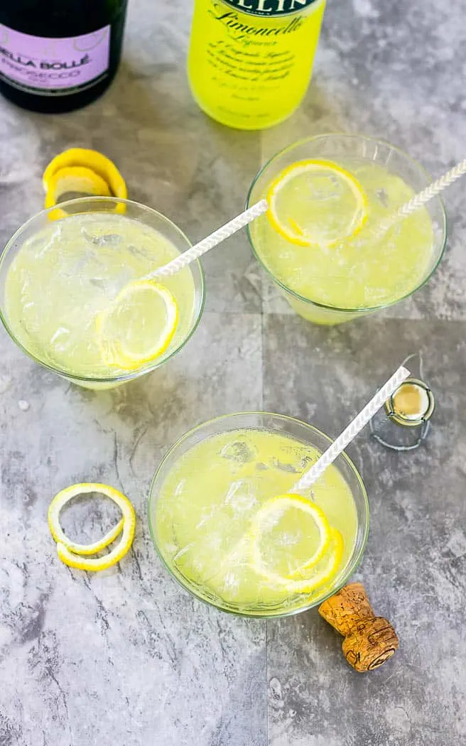 Overhead of 3 LImoncello Ladies with straws in them on a gray surface.