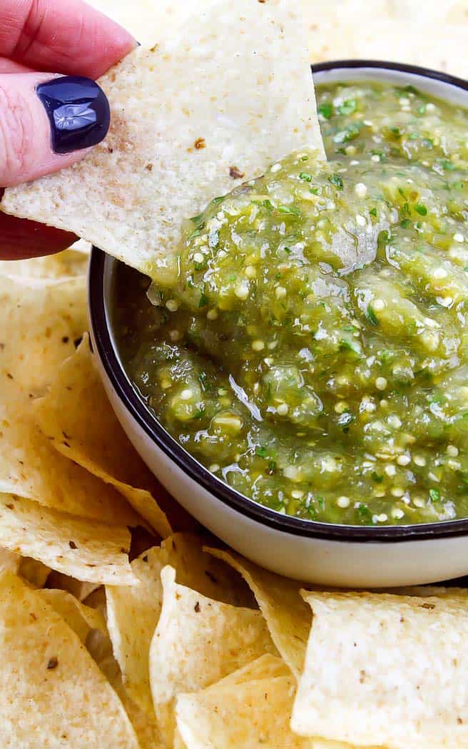 chip dipping in green salsa