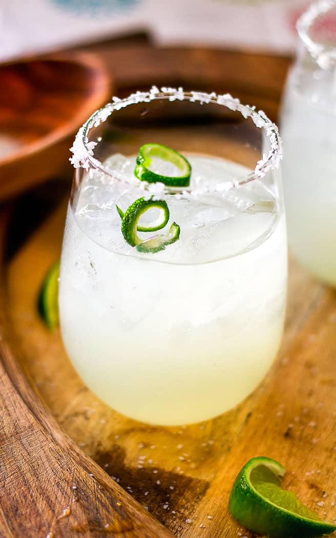 close up of cocktail with lime garnish on wood tray