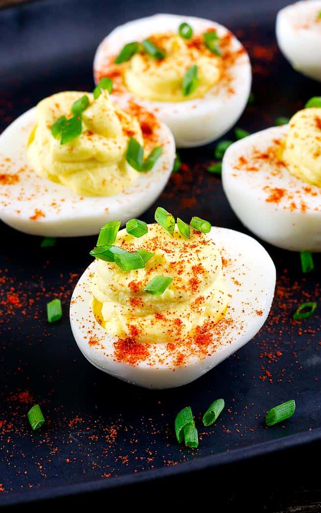 four deviled eggs on a black platter