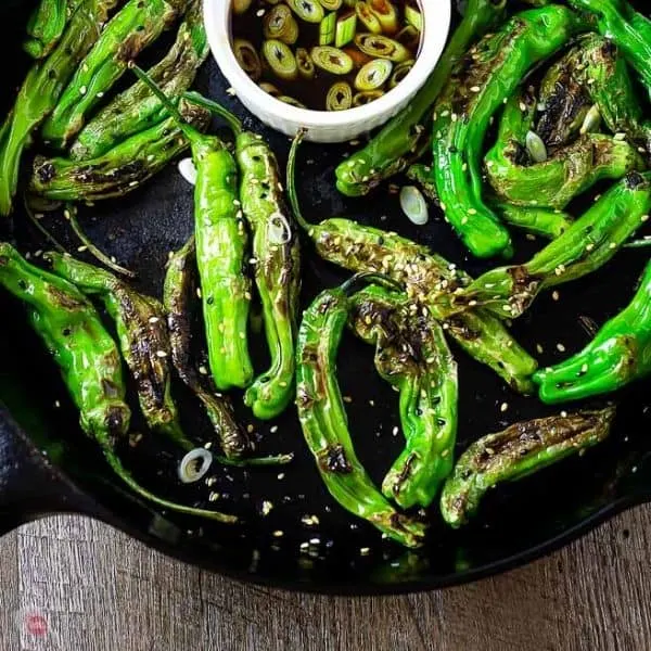 close up of shishito peppers in a casst iron skillet