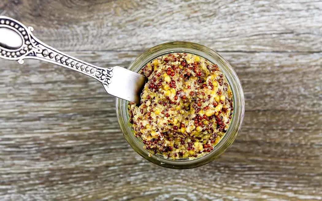 overhead picture of mustard in a jar with a spreader