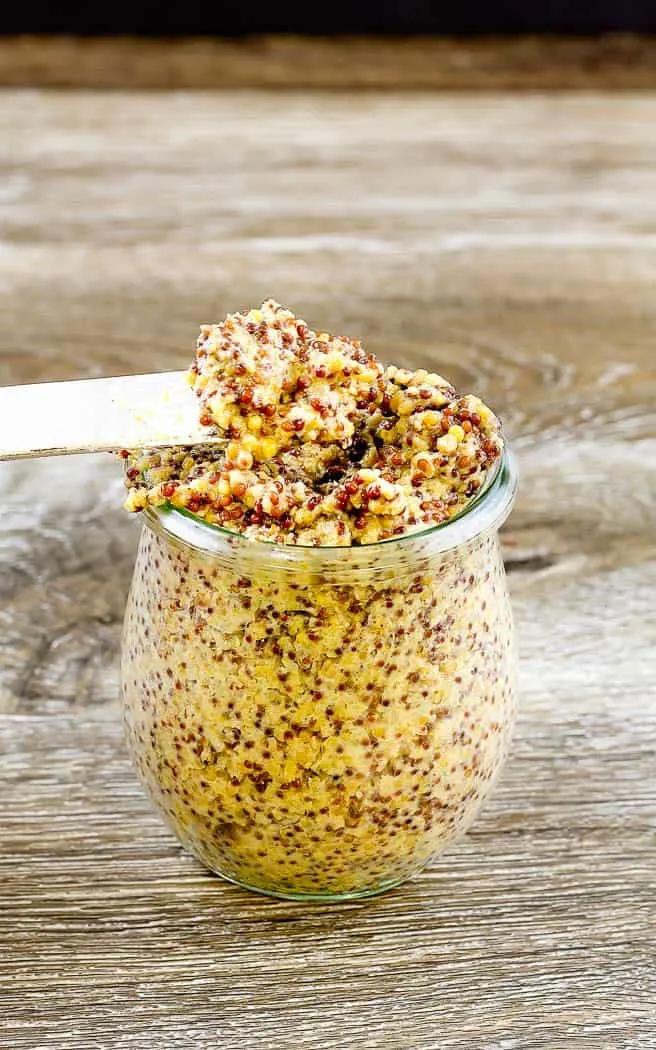 grainy whole grain mustard on a spreader from a jar