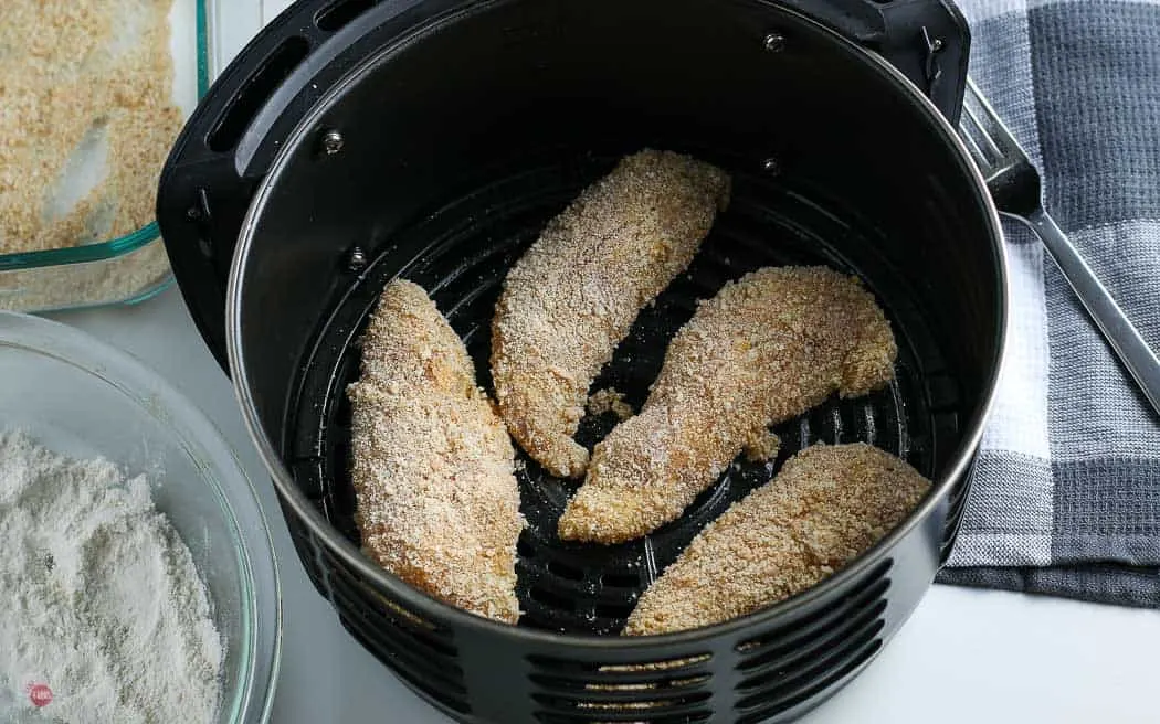 coated chicken tenders in an air fryer basket