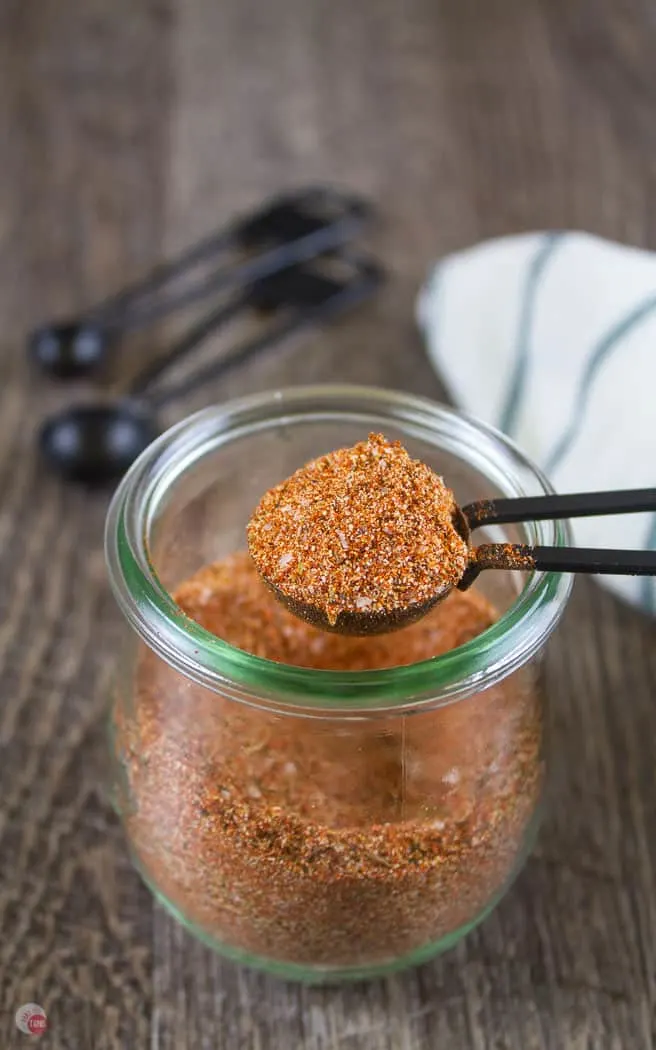 cajun seasoning in a clear jar with a black measuring spoon