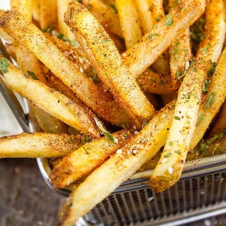 close up of wire basket of french fries with fry seasoning on them