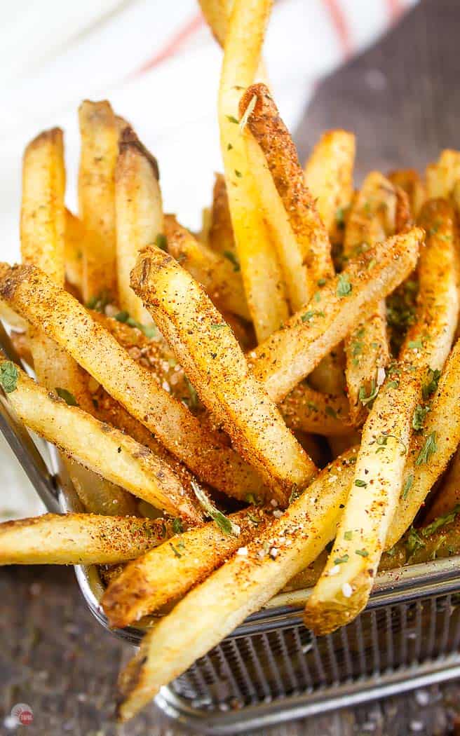 wire basket of fries with seasoning on them