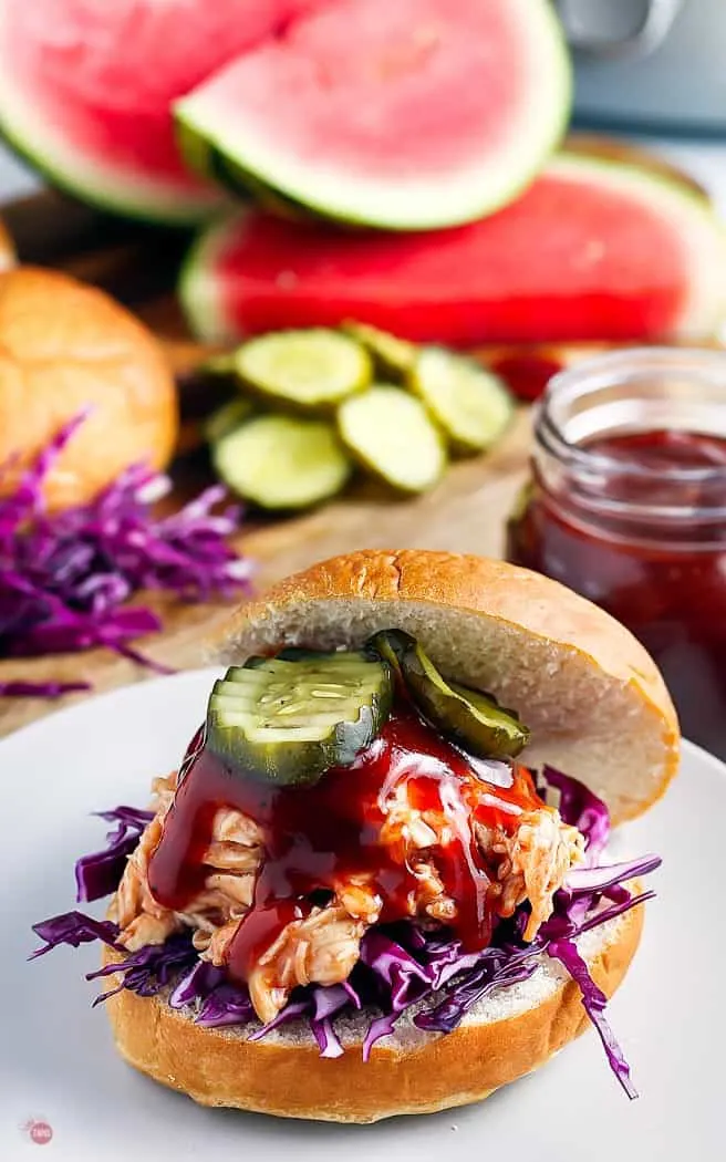 closeup of bbq chicken on a hamburger bun with pickles