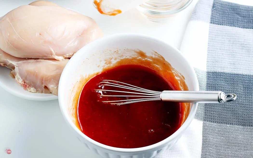 homemade bbq sauce in a white bowl with a metal whisk