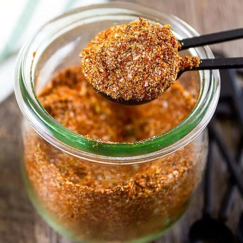 square photo of taco seasoning being scooped out of a clear jar