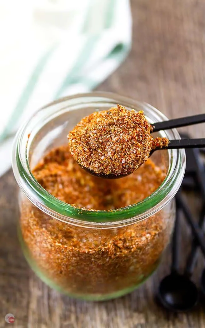 overhead side angle of a jar of spices with a black measuring spoon scooping out some