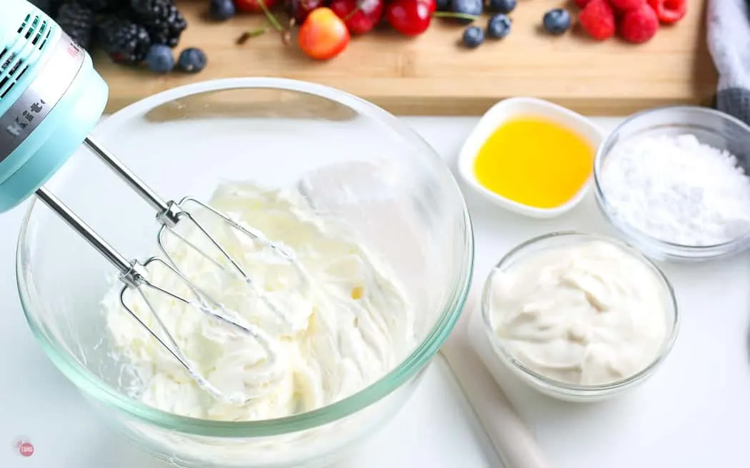 cream cheese in a clear bowl with beaters