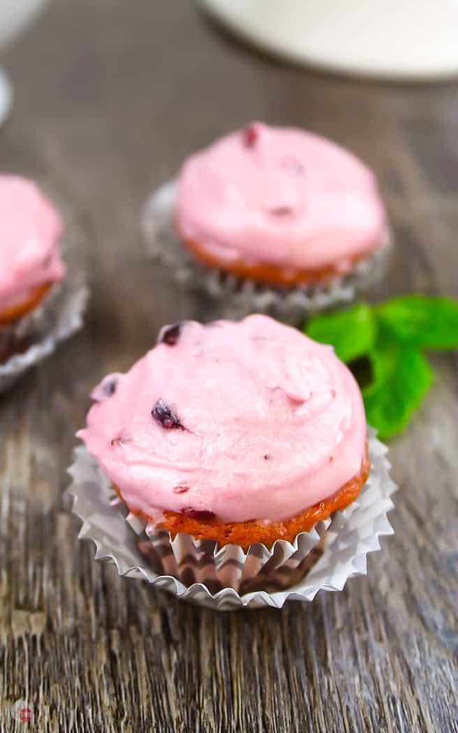 pink cupcakes in wrappers on a wood board