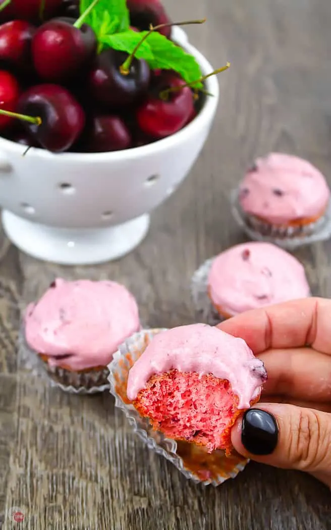 hand holding a mini cupcake with a bite taken out of it