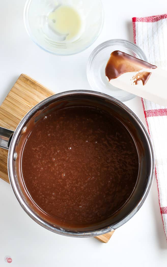 fudge sauce in a metal pan with a spatula next to it