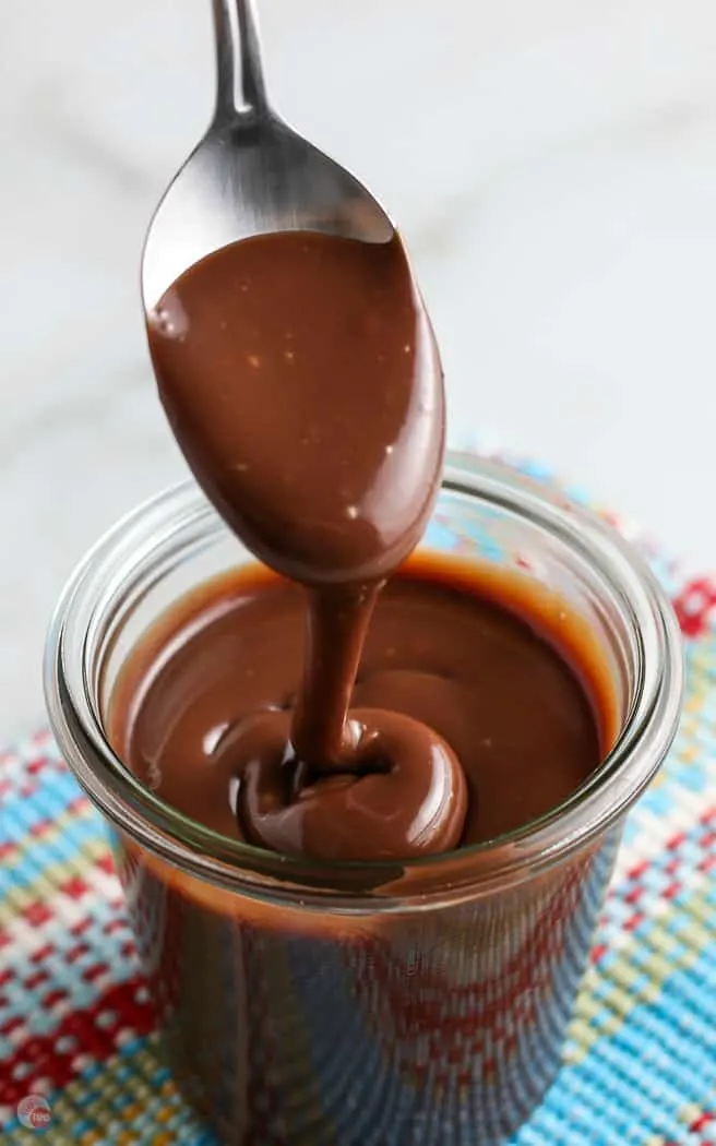 hot fudge sauce dripping from a spoon into a clear jar