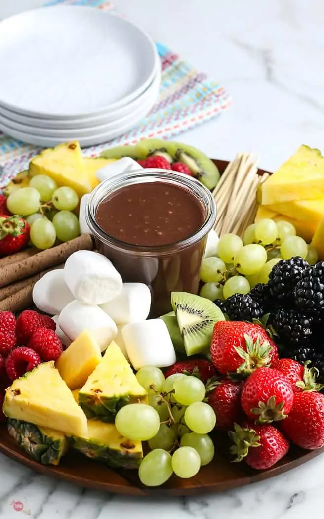 chopped fruit on a board with fudge sauce