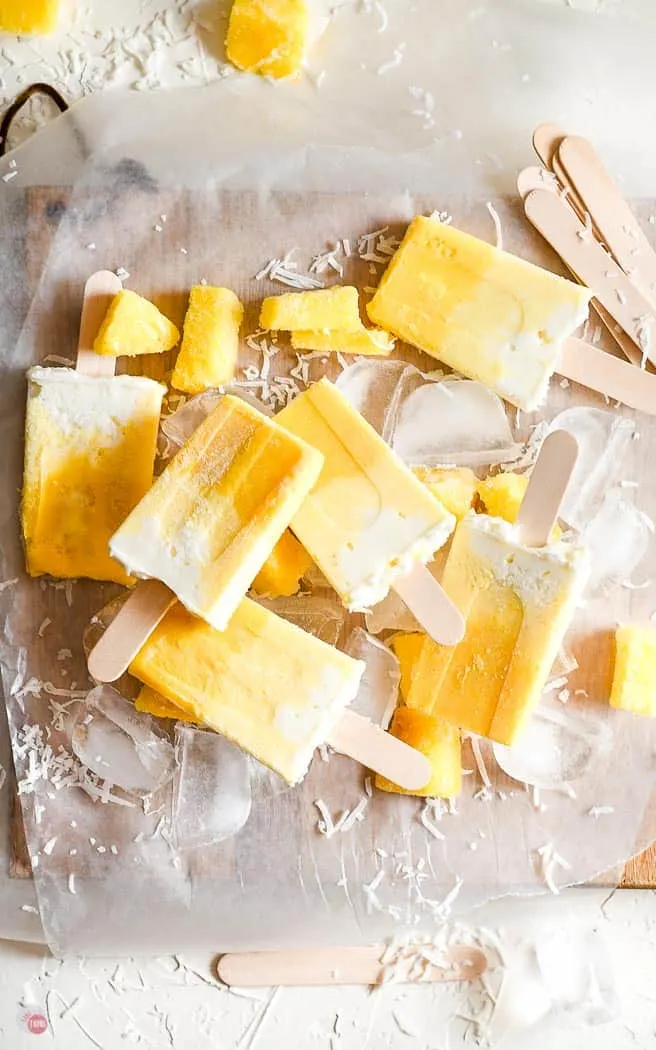 ombre fruit popsicles on parchment paper with ice cubes