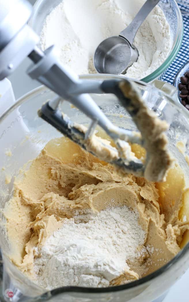 flour being added to cookie dough batter in a bowl