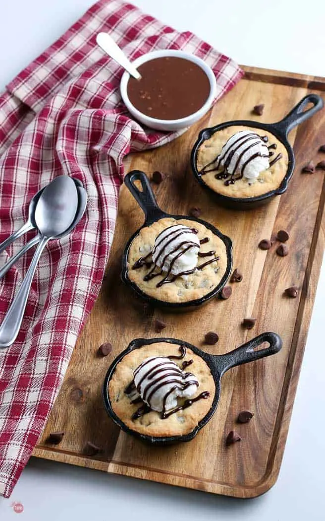 overhead picture of three skillet cookies on a wood cutting board