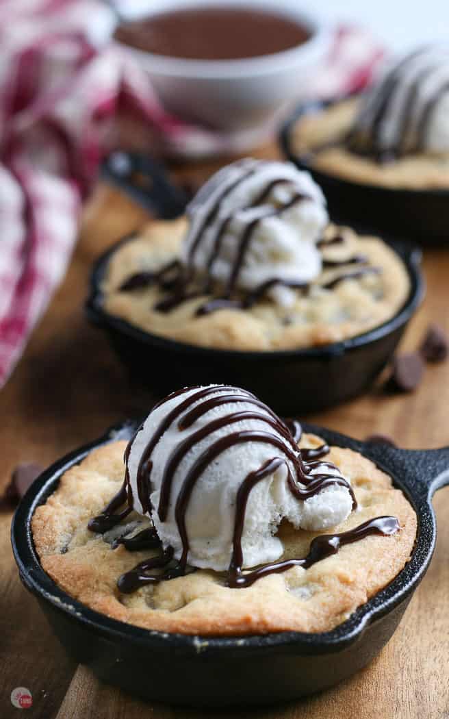 two pizookie cookies topped with ice cream on a wood board