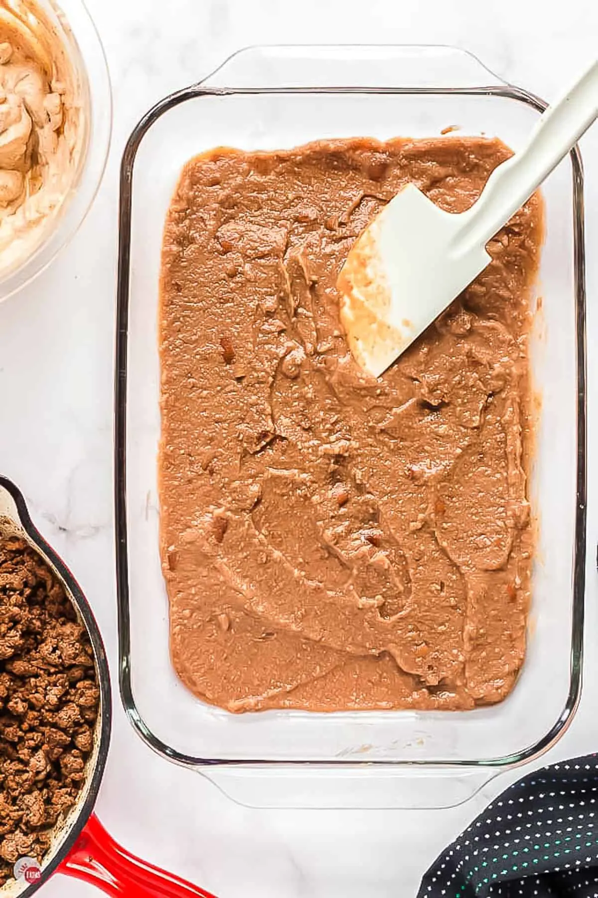 refried beans in a clear dish with spatula