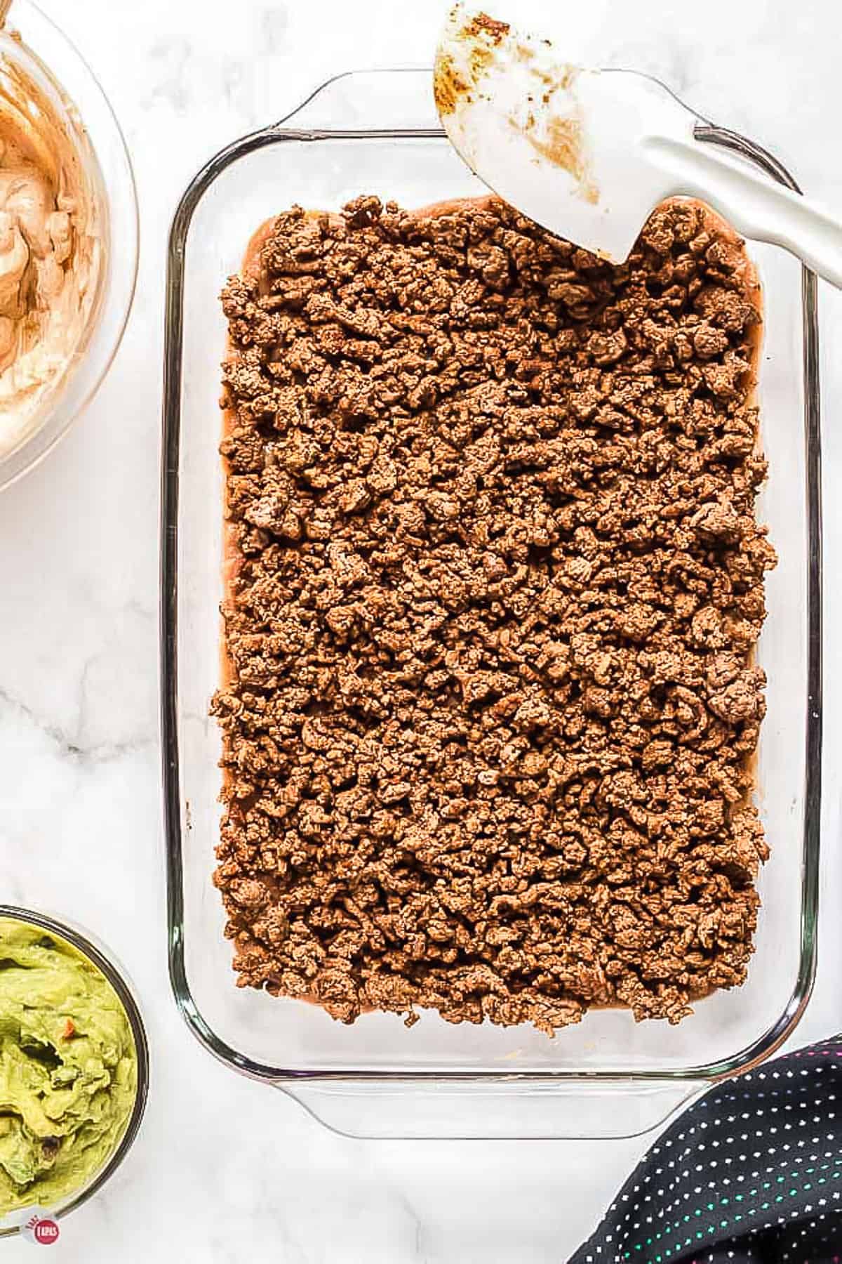 ground beef in a clear dish with spatula